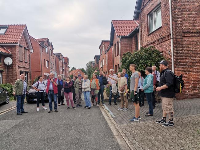 Menschengruppe steht vor einer Häuserreihe